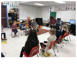 Mrs. Vacchino is demonstrating dance movements to her class 